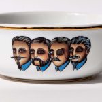 Detail view of porcelain shaving bowl with illustration of Victorian-era gentlemen portraits, gold trim