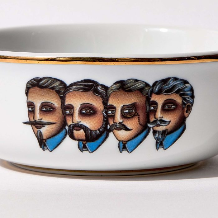 Detail view of porcelain shaving bowl with illustration of Victorian-era gentlemen portraits, gold trim