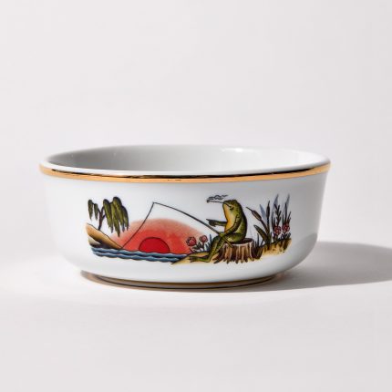 Porcelain shaving bowl with illustration of anthropomorphic frog fishing and riverside backdrop, gold trim