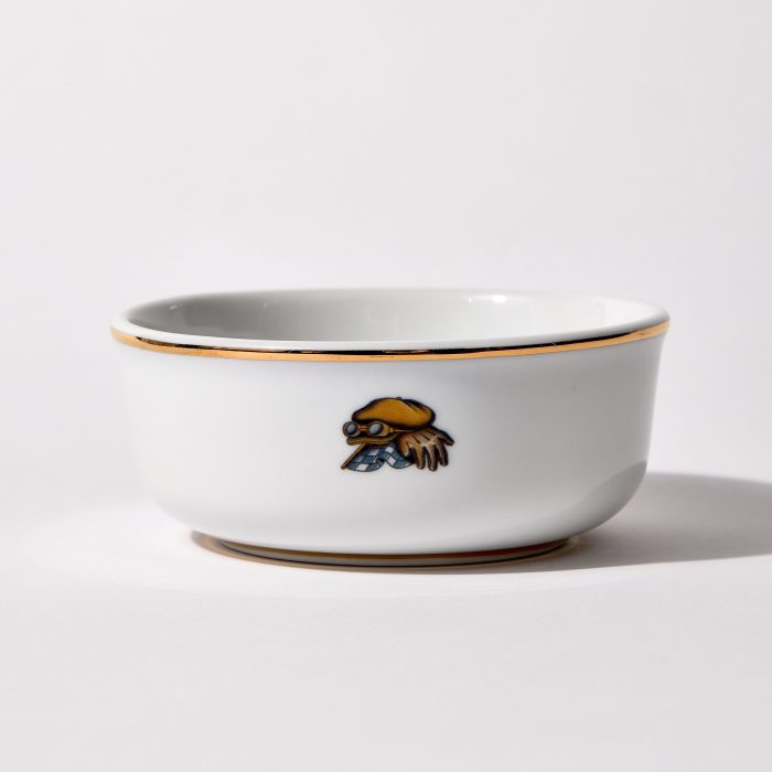 Back of shaving bowl with illustration of vintage motorcycle cap, gloves, goggles, and checkered flag