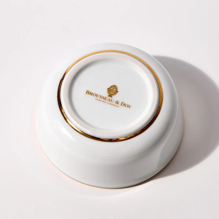 Bottom of porcelain shaving bowl showing gold Brousseau & Dov logo and gold trim around foot