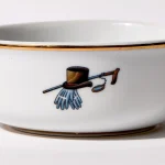 Detail view of back of shaving bowl with illustration of vintage top hat, cane, monocle, gold trim