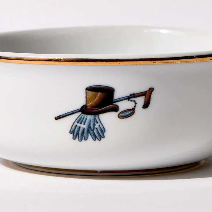 Detail view of back of shaving bowl with illustration of vintage top hat, cane, monocle, gold trim