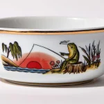 Detail view of porcelain shaving bowl with illustration of anthropomorphic frog fishing and riverside backdrop, gold trim