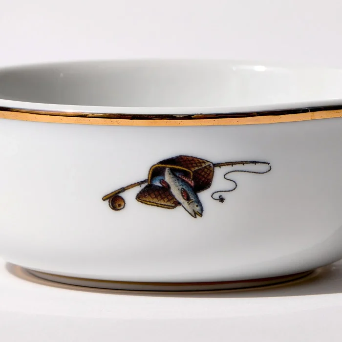 Detail view of back of shaving bowl with illustration of vintage fishing creel, fish, rod, and reel, gold trim