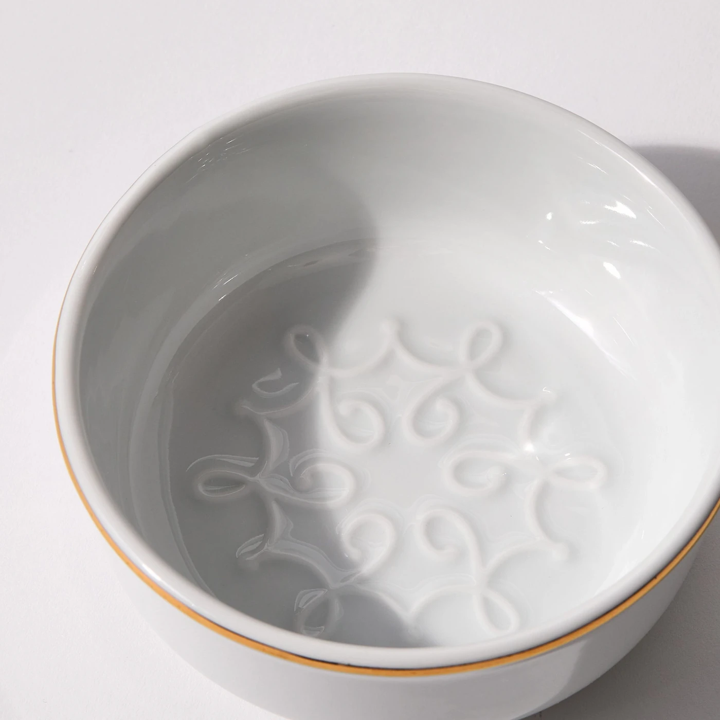 Interior view of porcelain shaving bowl showing lather feature and gold trim against light background
