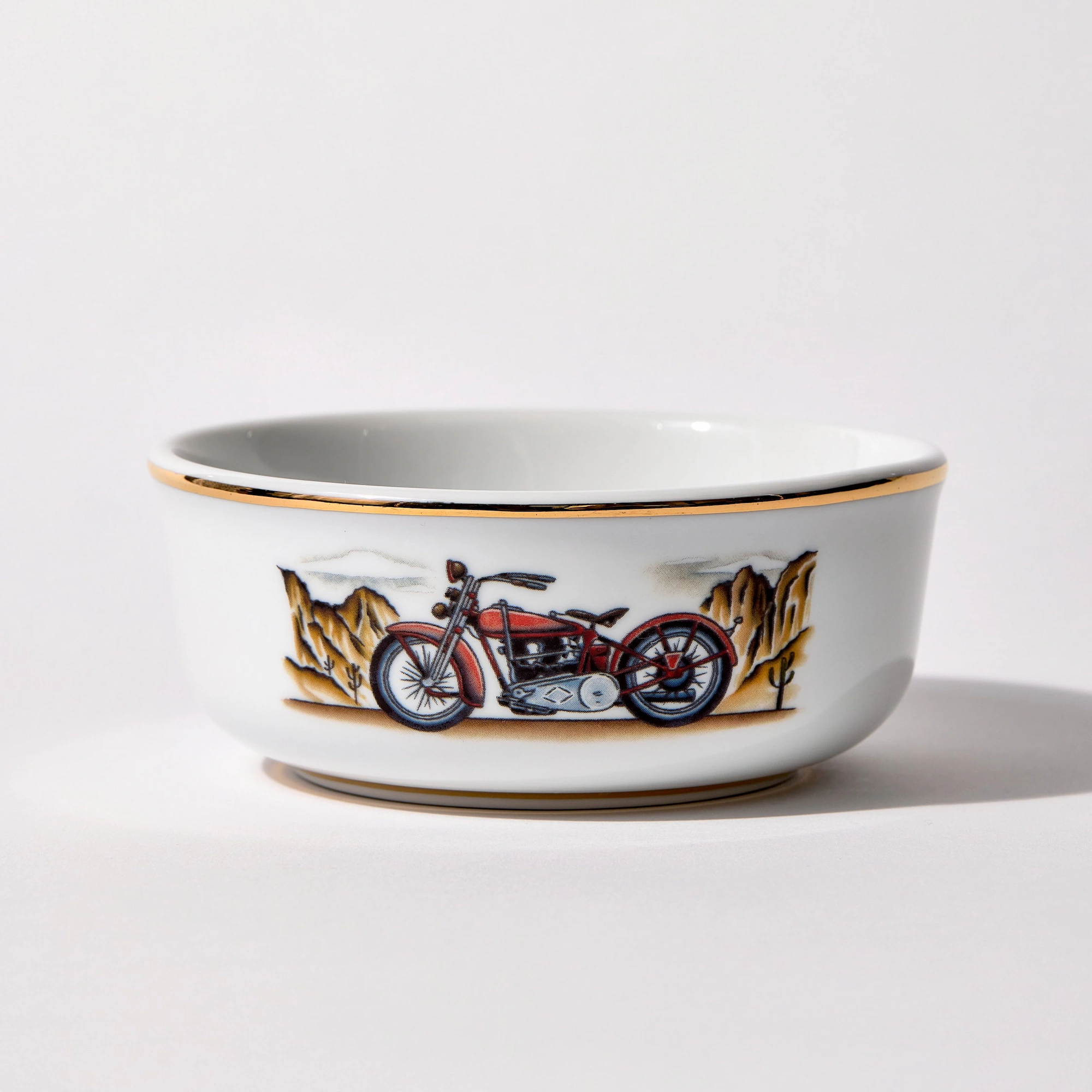 Motorcycle_Primary_300ppi_Enhanced_WebP_2000 Porcelain shaving bowl with illustration of vintage Harley-Davidson motorcycle and desert backdrop, gold trim