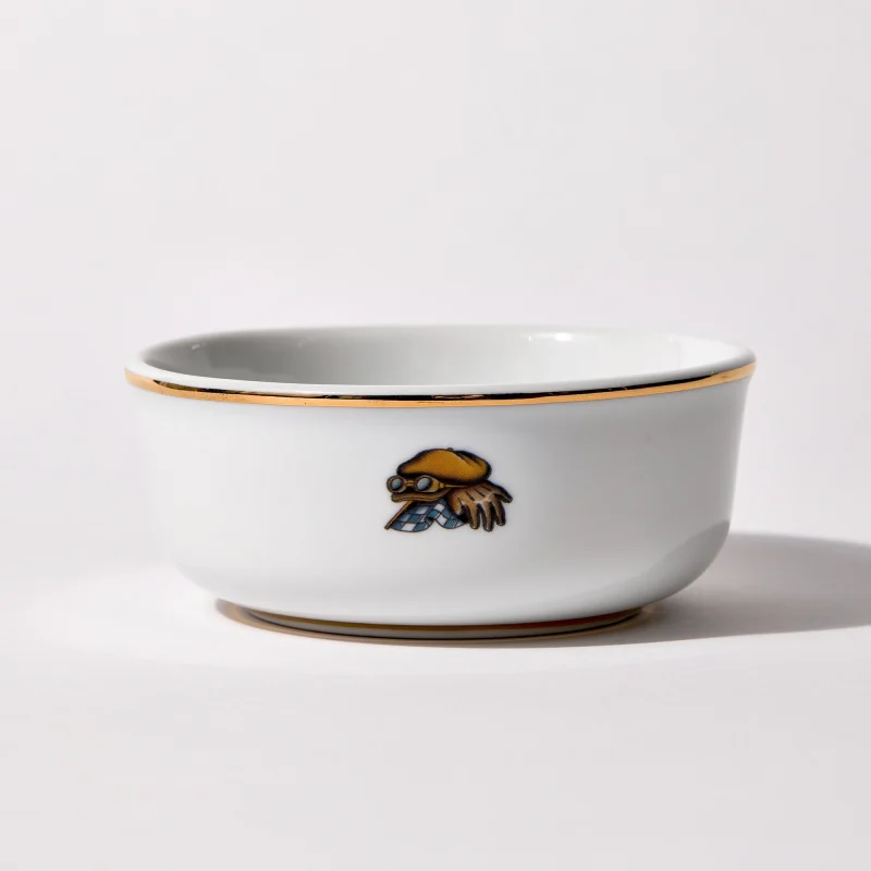 Back of shaving bowl with illustration of vintage motorcycle cap, gloves, goggles, and checkered flag, gold trim