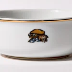 Detail view of back of shaving bowl with illustration of vintage motorcycle cap, gloves, goggles, and checkered flag