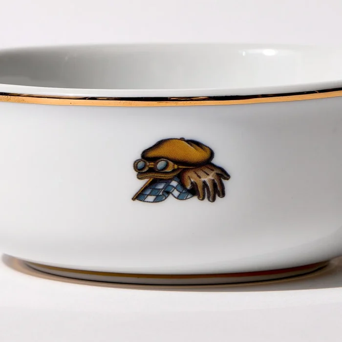 Detail view of back of shaving bowl with illustration of vintage motorcycle cap, gloves, goggles, and checkered flag