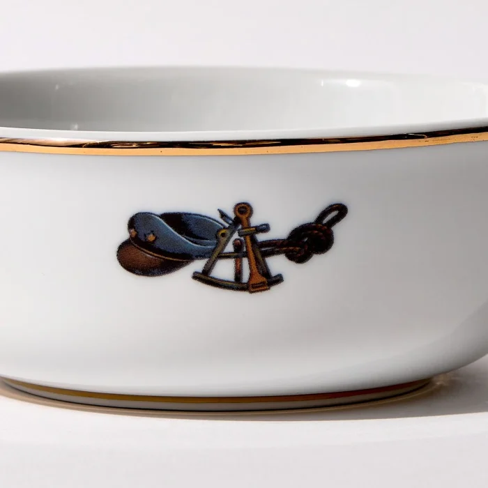 Detail view of back of shaving bowl with illustration of vintage captain's hat, sextant, and coiled rope, gold trim