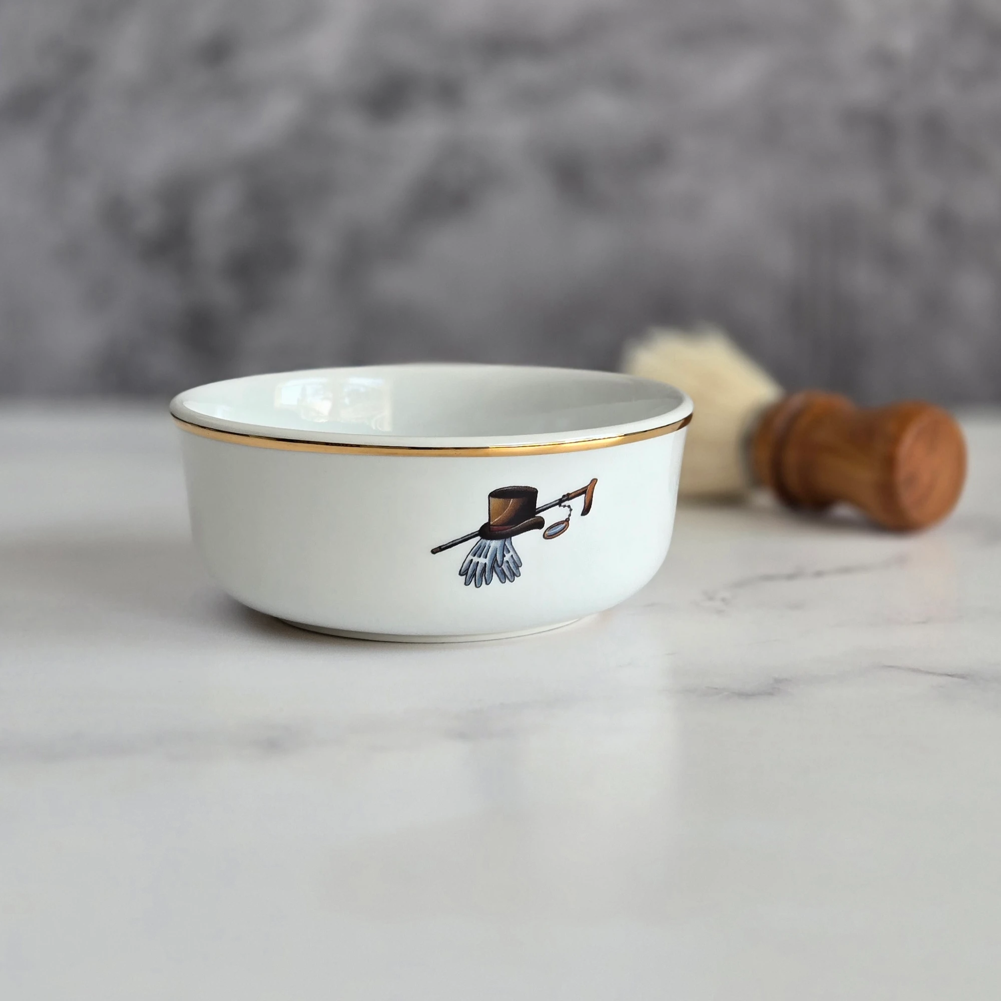 Porcelain shaving bowl with vintage-style illustration beside a shaving brush